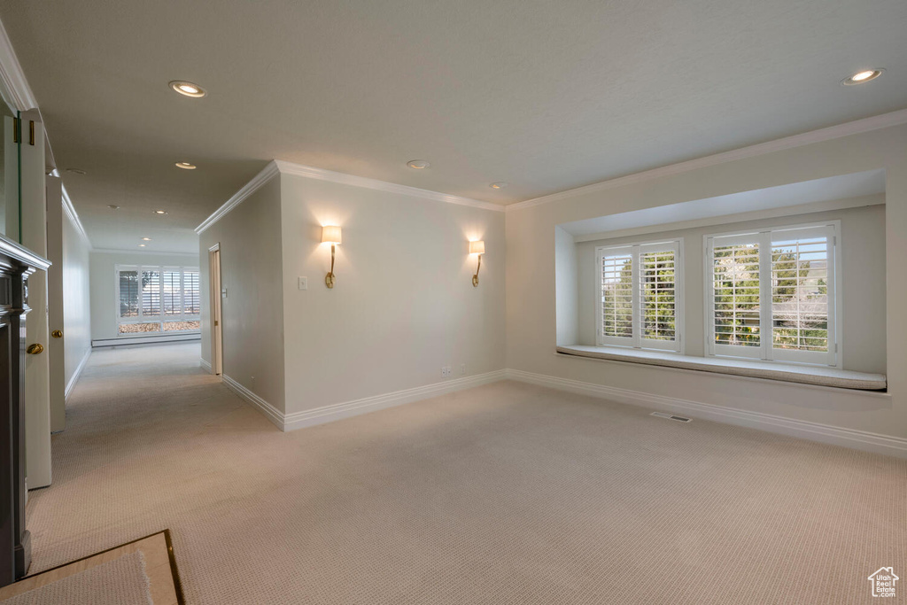 Unfurnished room featuring ornamental molding, plenty of natural light, and light carpet