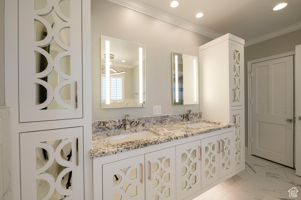 Bathroom featuring ornamental molding, dual sinks, tile flooring, and vanity with extensive cabinet space
