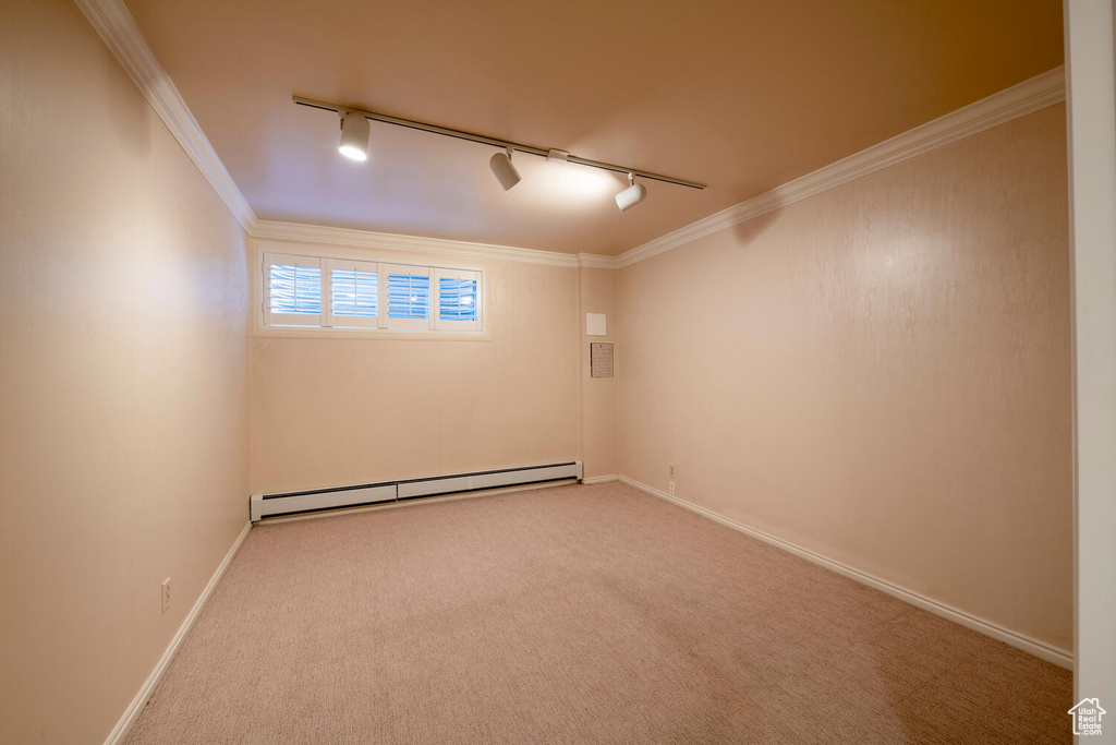 Empty room with light colored carpet, crown molding, a baseboard radiator, and track lighting