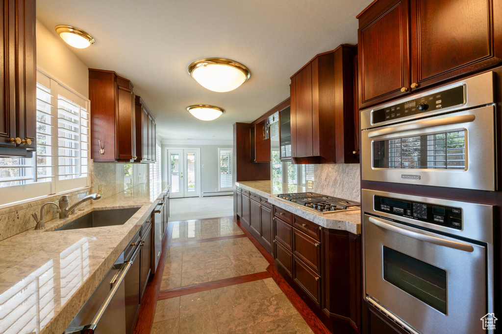 Kitchen with backsplash, light stone countertops, appliances with stainless steel finishes, and light tile floors