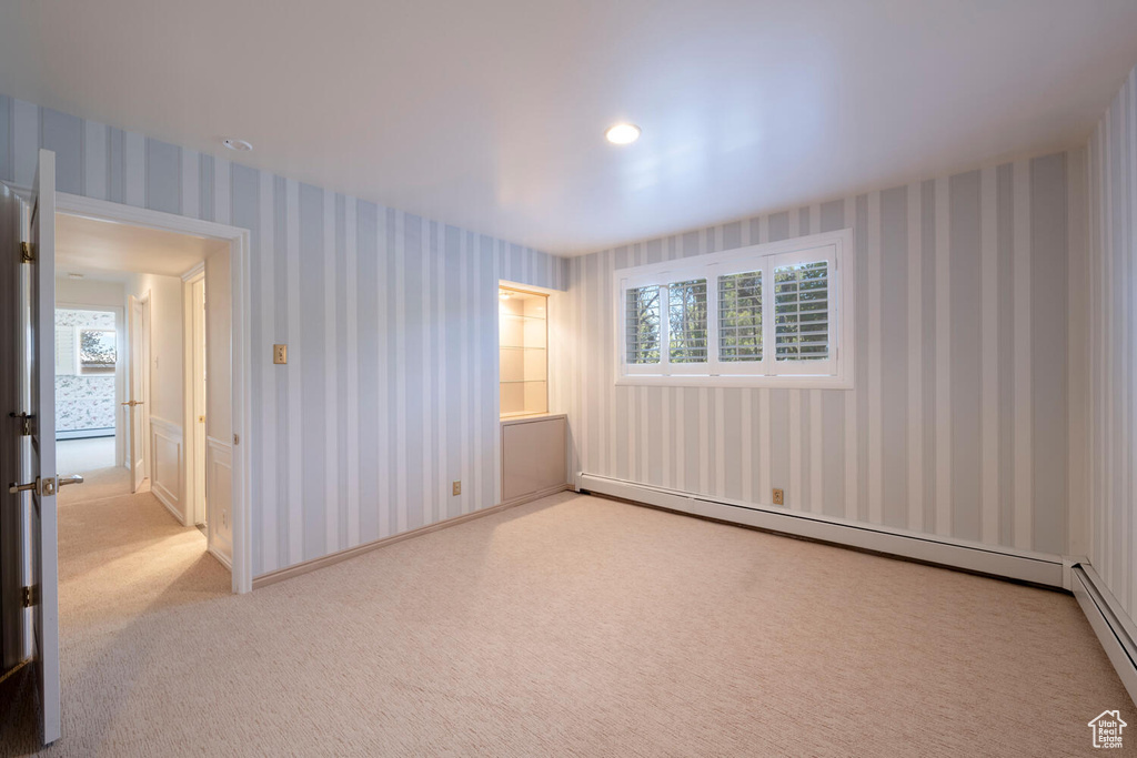 Unfurnished room with light colored carpet and baseboard heating