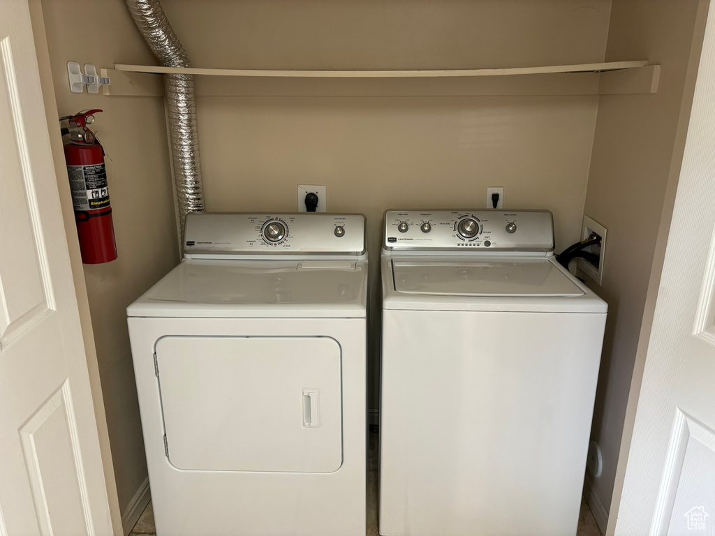 Clothes washing area featuring hookup for an electric dryer, washer hookup, and washer and clothes dryer