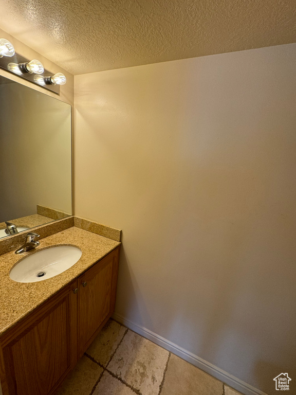 Bathroom featuring a textured ceiling, vanity, and tile floors