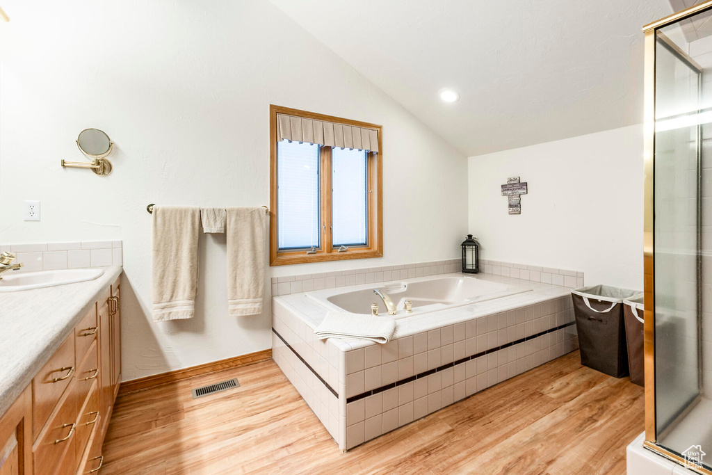 Bathroom with shower with separate bathtub, vanity, hardwood / wood-style floors, and lofted ceiling