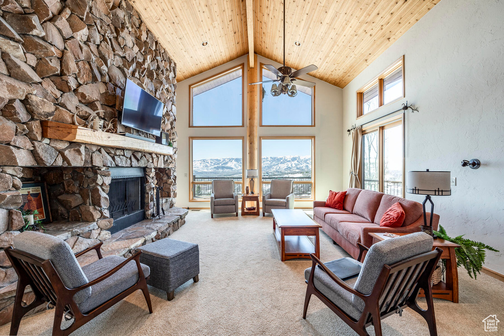 Living room featuring a mountain view, high vaulted ceiling, a fireplace, wood ceiling, and light colored carpet