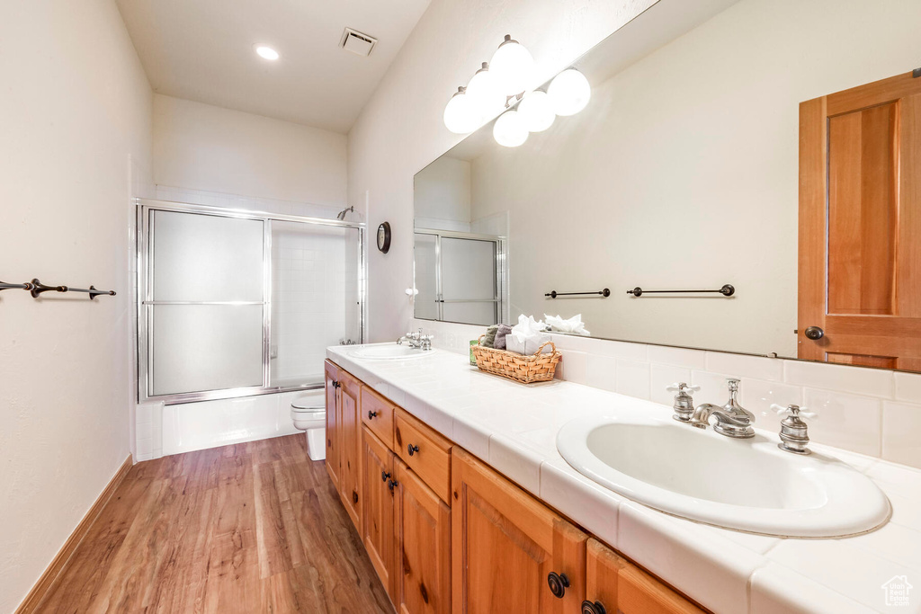 Bathroom with hardwood / wood-style floors, toilet, and dual vanity