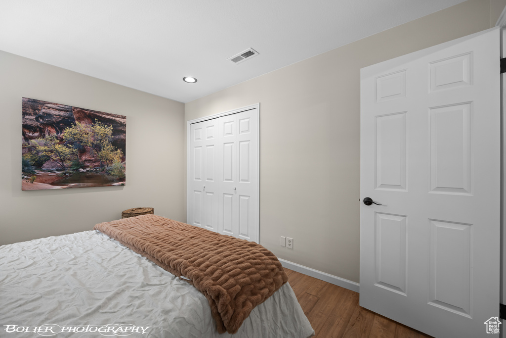 Bedroom with dark hardwood / wood-style flooring and a closet