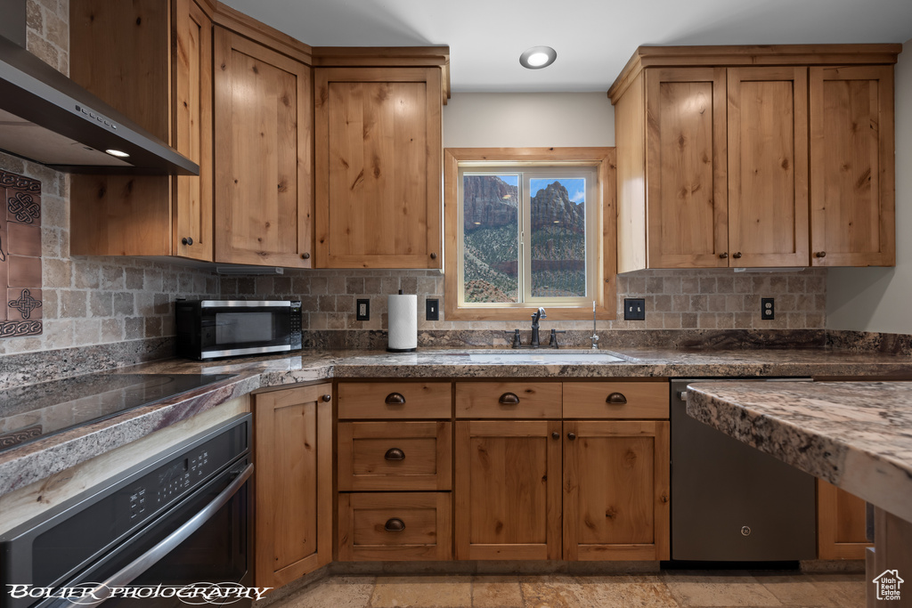 Kitchen with sink, light tile flooring, wall chimney range hood, backsplash, and black appliances
