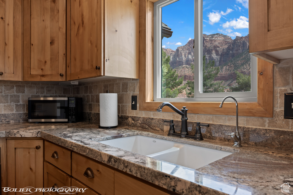 Kitchen with light stone counters, sink, a mountain view, and tasteful backsplash