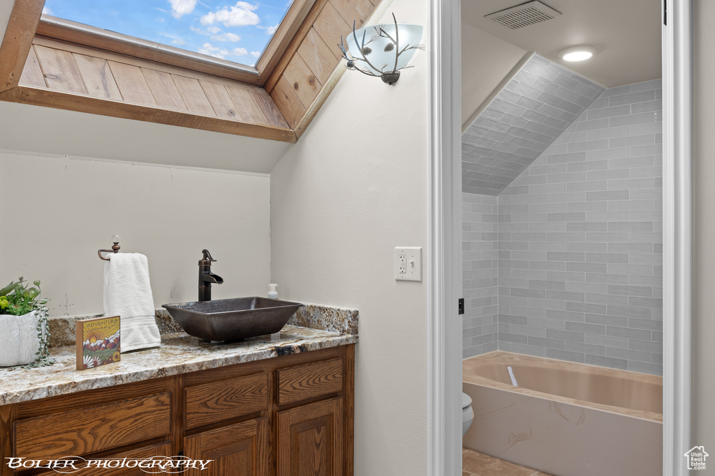 Bathroom featuring vanity, toilet, and vaulted ceiling with skylight