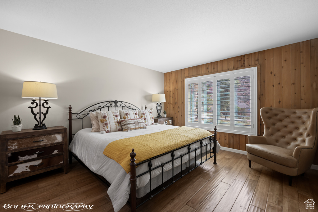 Bedroom featuring wood walls and dark hardwood / wood-style flooring