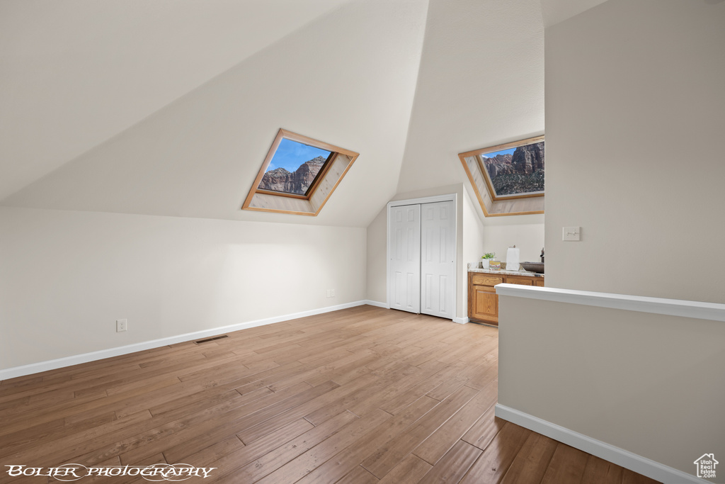 Bonus room with light hardwood / wood-style flooring and vaulted ceiling with skylight