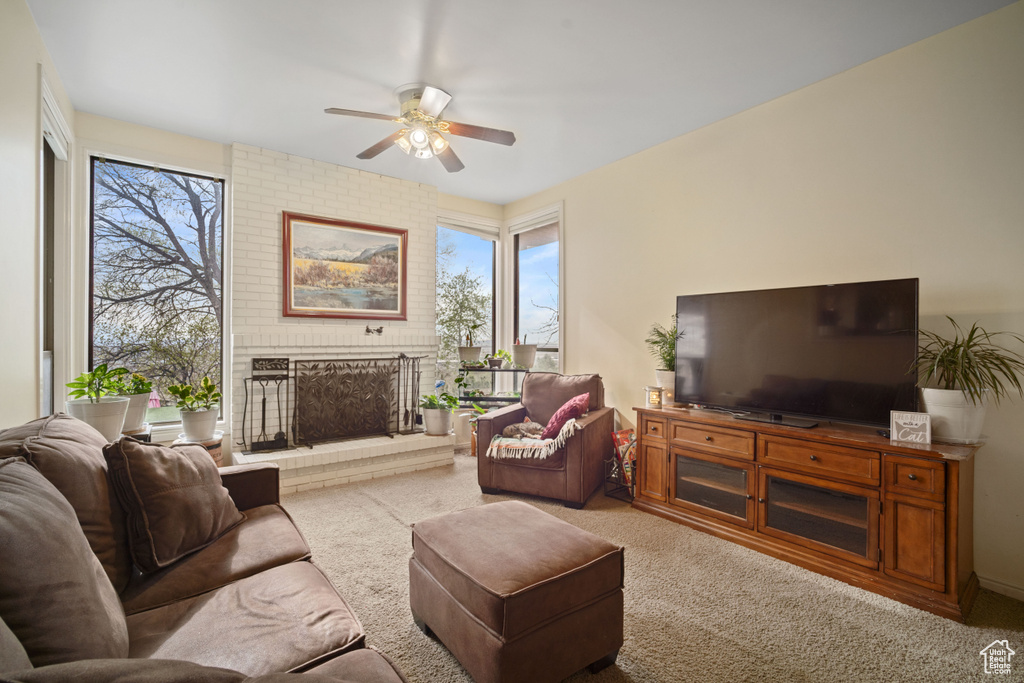 Living room featuring light carpet, ceiling fan, and a brick fireplace