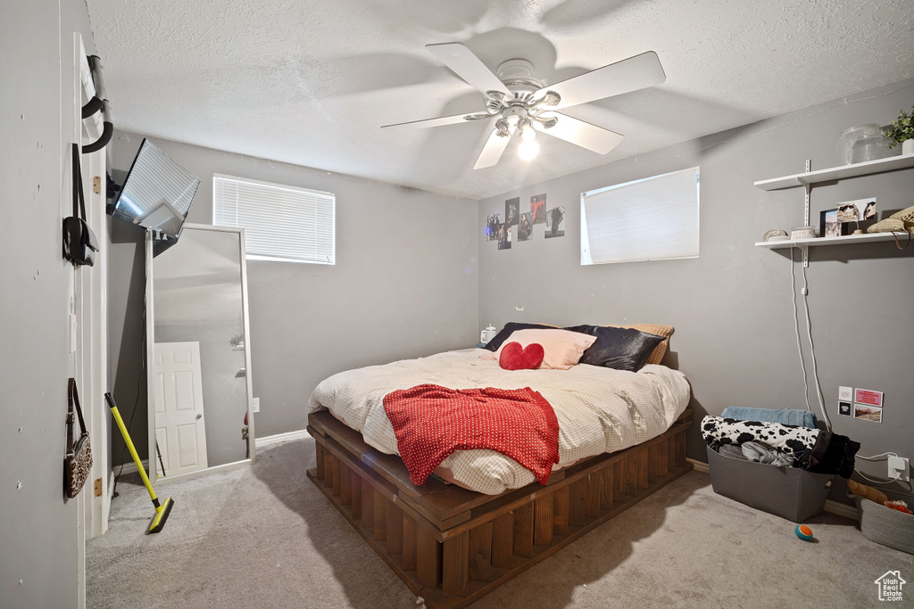 Bedroom with a textured ceiling, ceiling fan, and light carpet