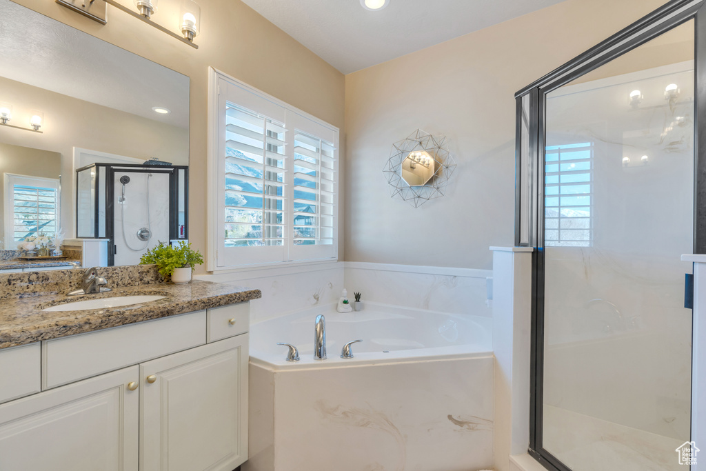 Bathroom with a wealth of natural light, independent shower and bath, and vanity with extensive cabinet space