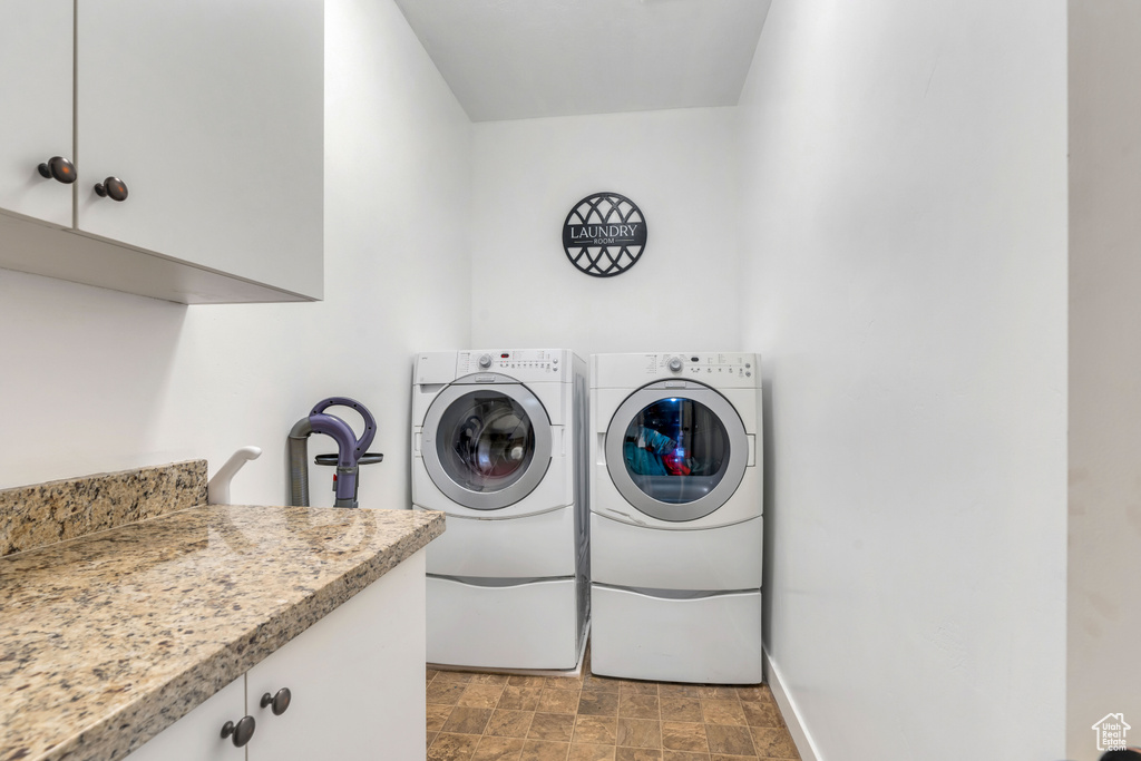 Clothes washing area with cabinets, separate washer and dryer, and light tile floors