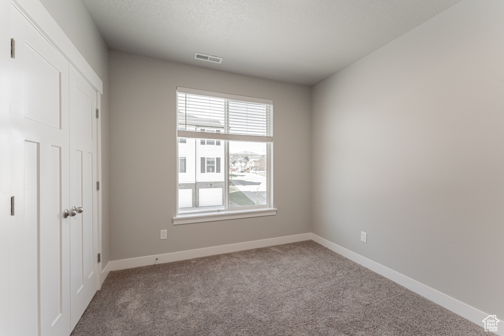 Carpeted spare room featuring a textured ceiling