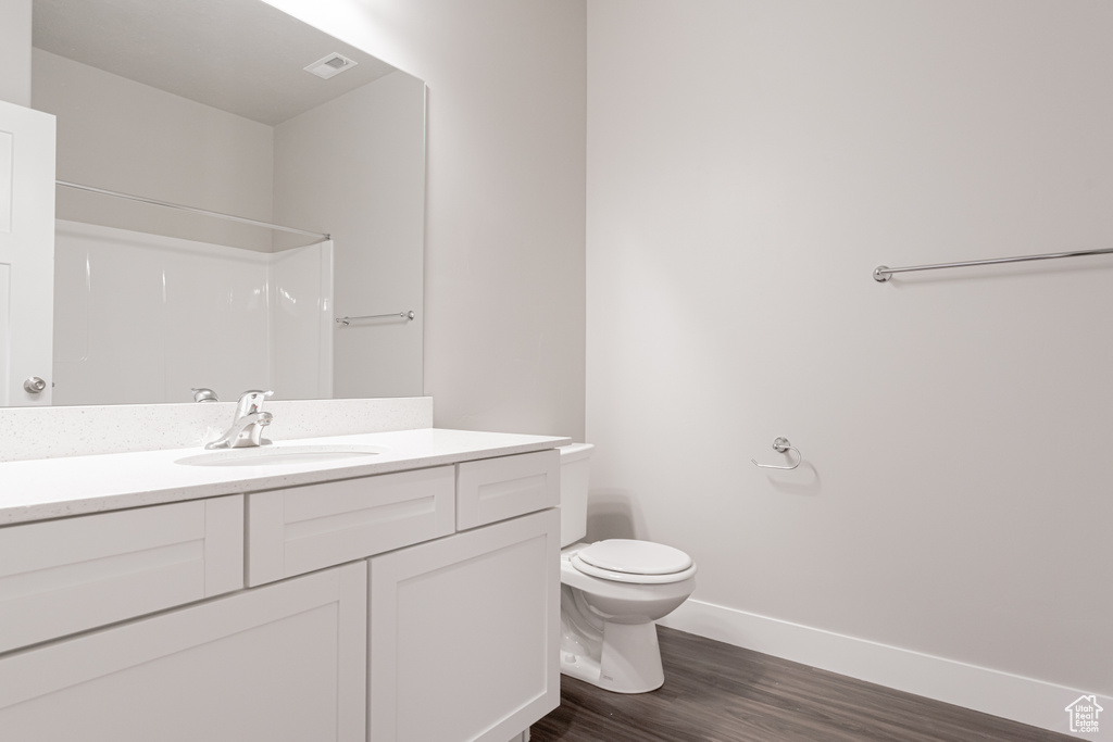 Bathroom with toilet, a shower, vanity, and wood-type flooring