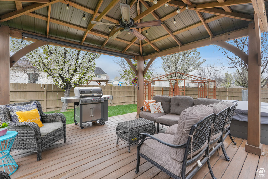 Wooden deck with ceiling fan, a grill, a gazebo, and an outdoor hangout area