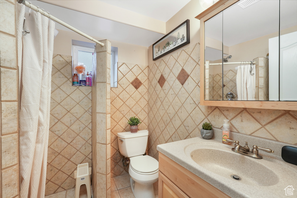 Bathroom featuring tile walls, backsplash, toilet, tile flooring, and vanity