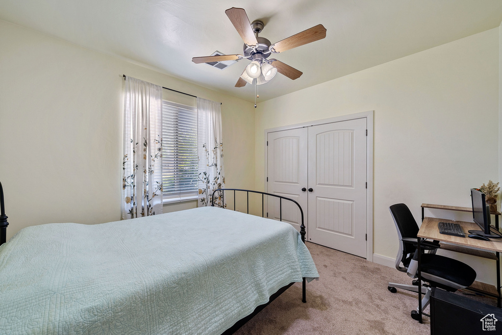 Bedroom with light colored carpet, ceiling fan, and a closet