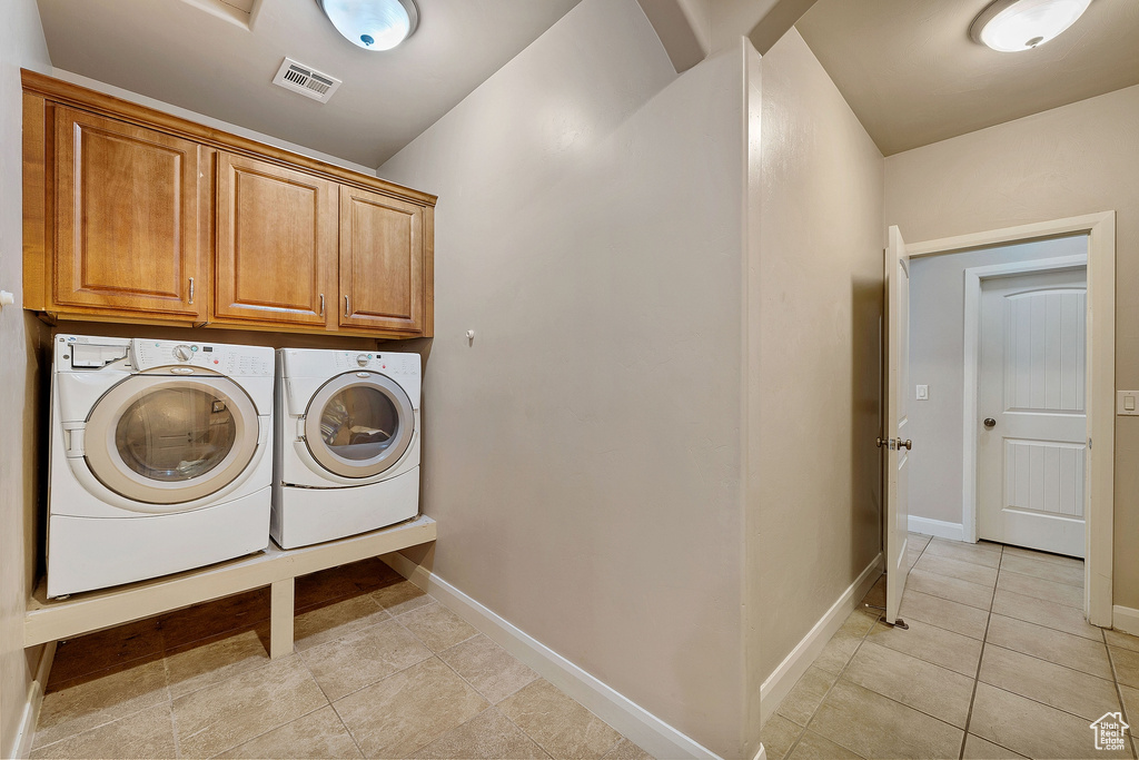 Laundry room with cabinets, light tile floors, and separate washer and dryer