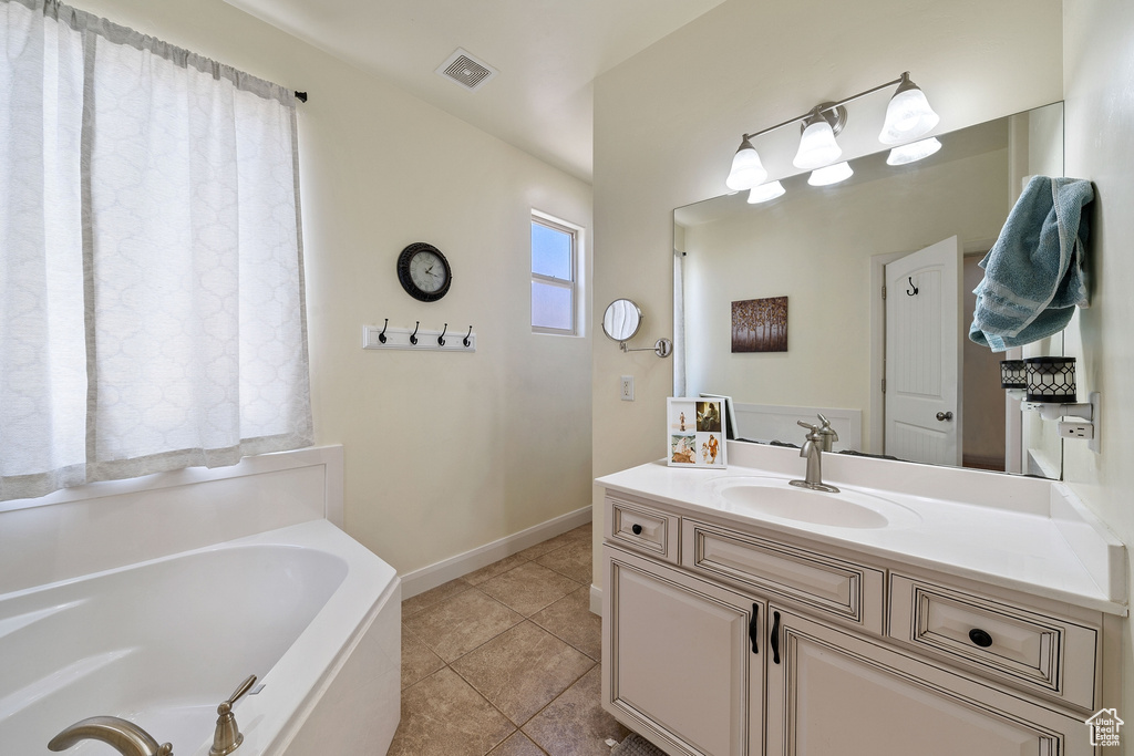 Bathroom featuring a bath to relax in, tile floors, and vanity