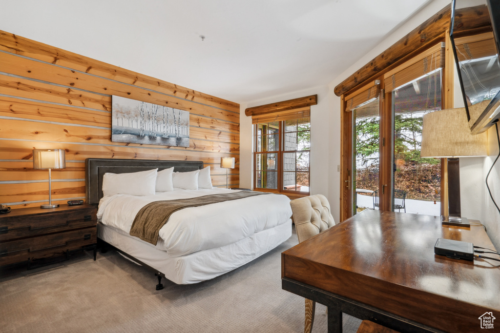 Bedroom featuring wooden walls, carpet, and access to outside