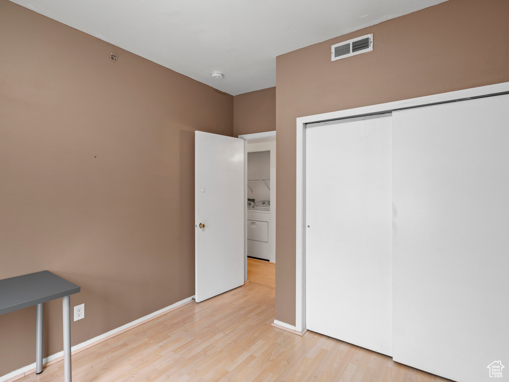 Unfurnished bedroom with a closet, light hardwood / wood-style floors, and washer / dryer