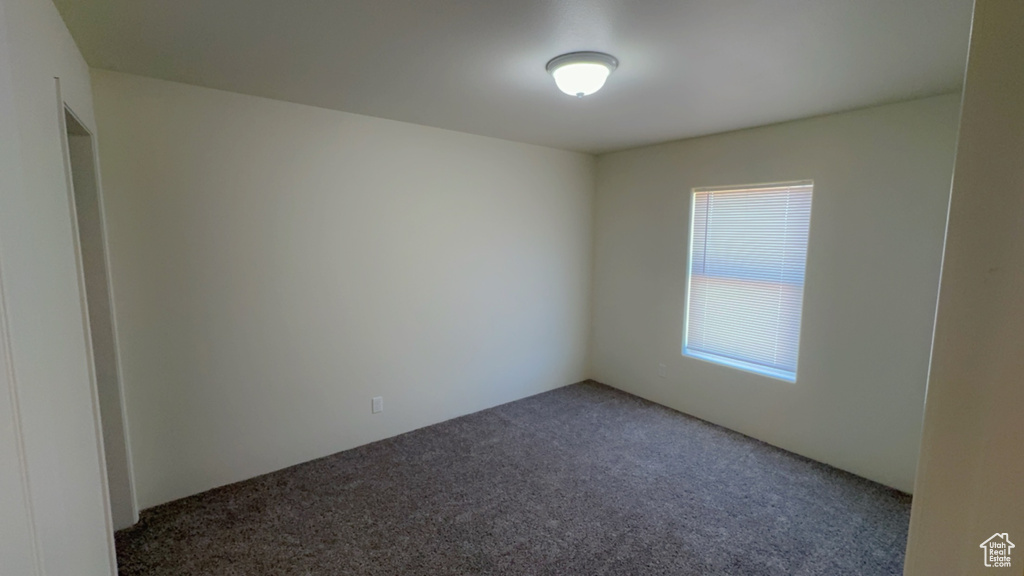 Unfurnished room featuring plenty of natural light and dark colored carpet