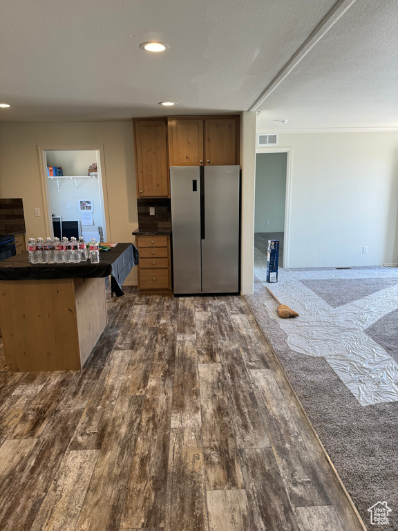 Kitchen with dark carpet, stainless steel fridge, and a textured ceiling
