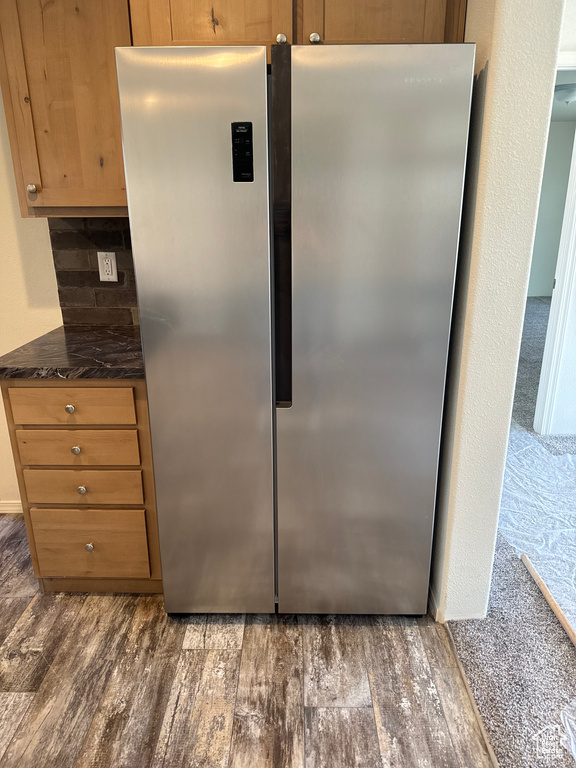 Kitchen featuring stainless steel refrigerator, dark carpet, and dark stone counters