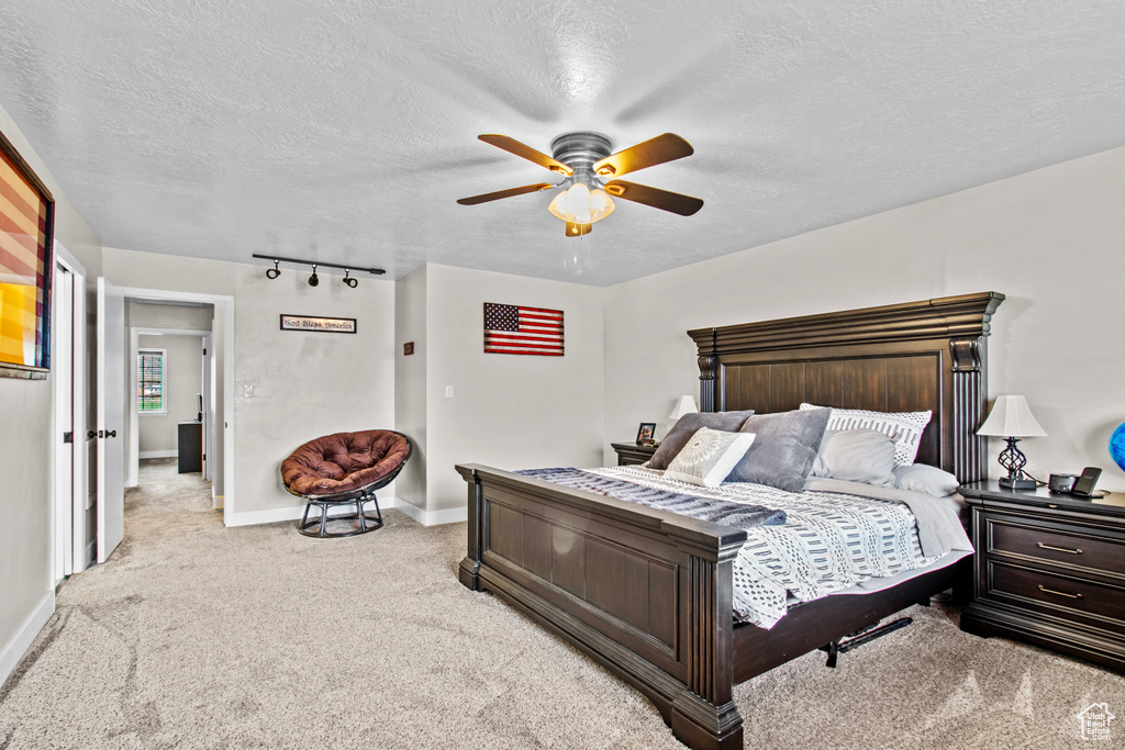 Carpeted bedroom with rail lighting, a textured ceiling, and ceiling fan