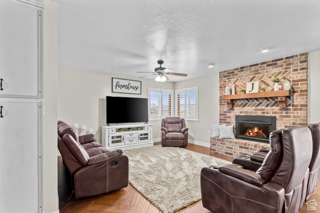 Living room with a textured ceiling, ceiling fan, and a brick fireplace