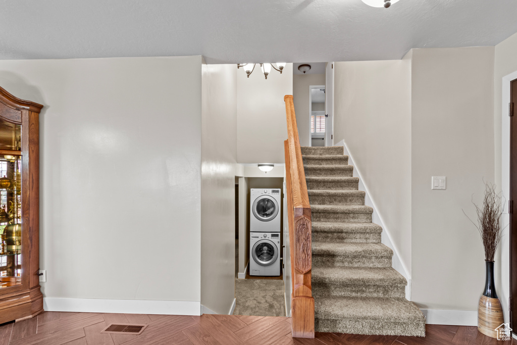 Stairway featuring plenty of natural light, dark parquet floors, and stacked washer and clothes dryer