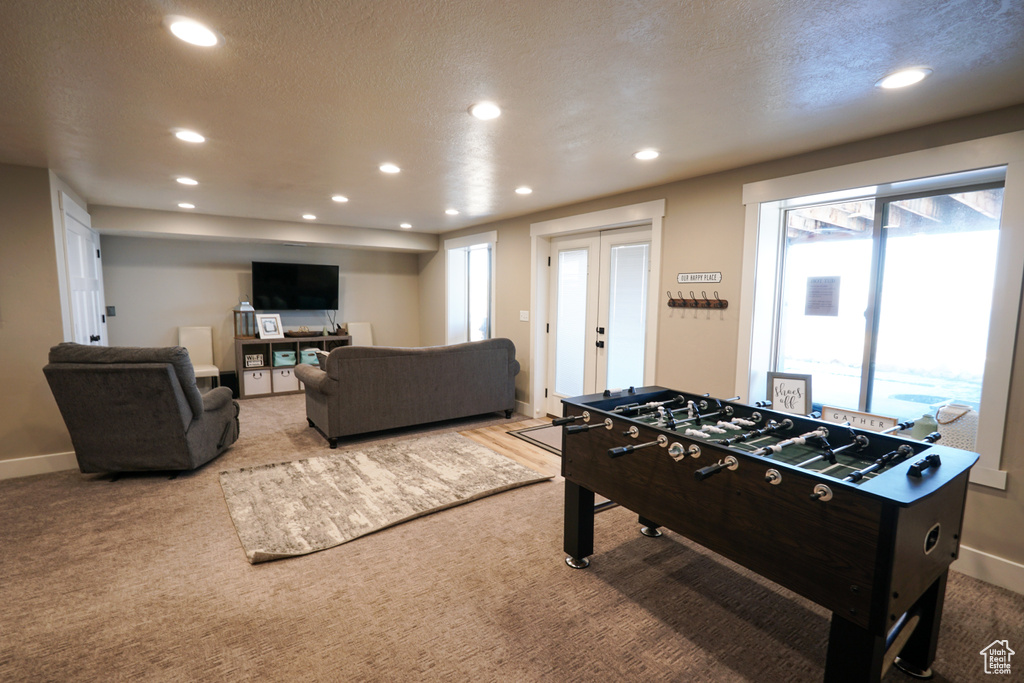 Recreation room featuring a textured ceiling, french doors, and light carpet