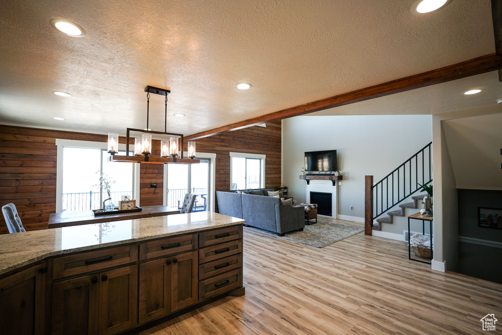Kitchen featuring light hardwood / wood-style floors, wooden walls, pendant lighting, and a textured ceiling