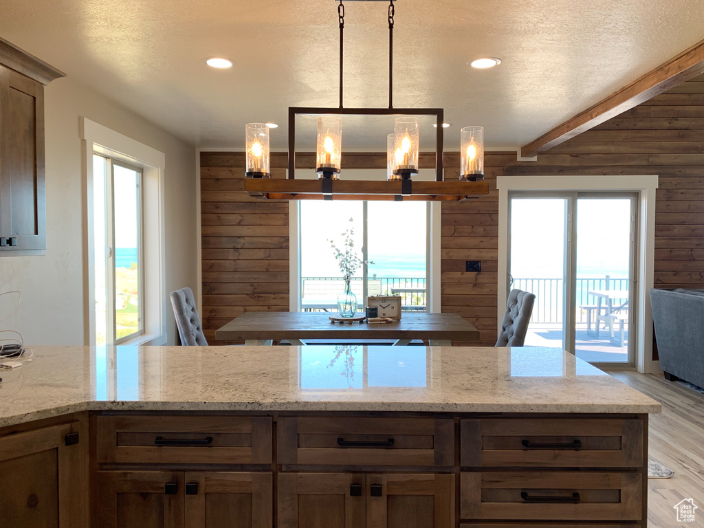 Kitchen featuring wood walls, pendant lighting, and plenty of natural light