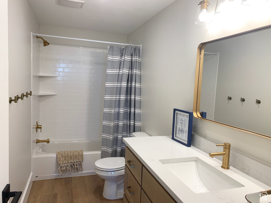 Full bathroom featuring shower / tub combo, toilet, vanity, and hardwood / wood-style floors