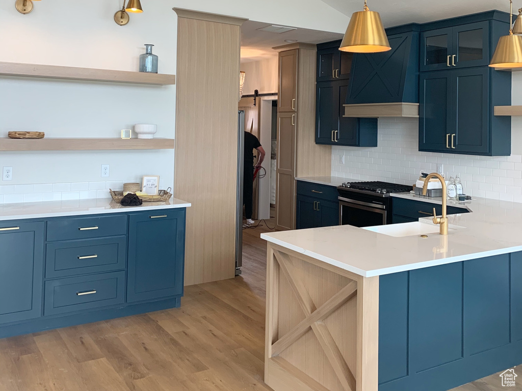 Kitchen featuring premium range hood, light wood-type flooring, backsplash, stainless steel gas stove, and lofted ceiling