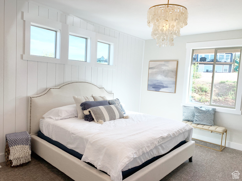 Bedroom with dark carpet, an inviting chandelier, and multiple windows