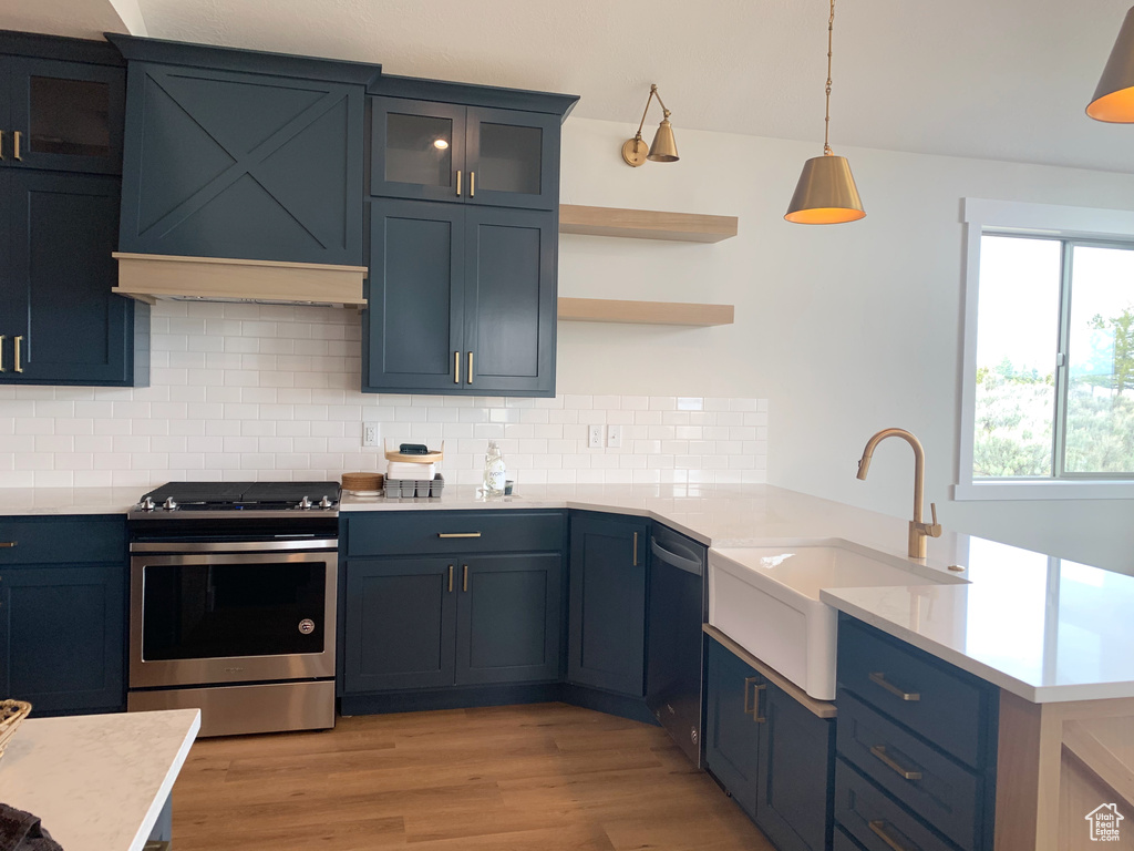 Kitchen featuring decorative light fixtures, light hardwood / wood-style floors, tasteful backsplash, and stainless steel appliances