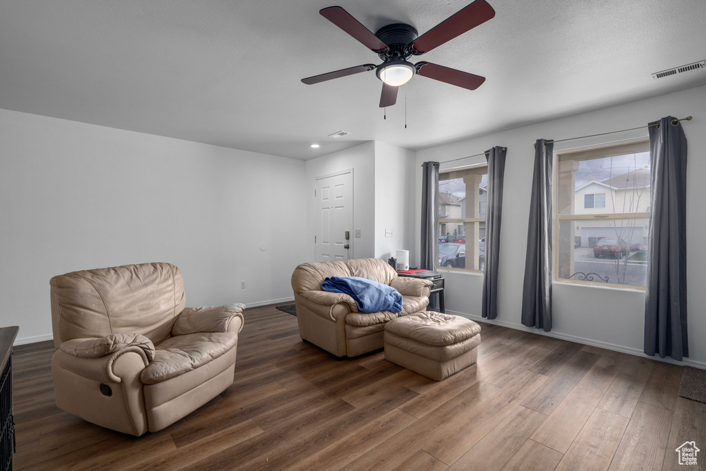 Living area with dark hardwood / wood-style floors and ceiling fan