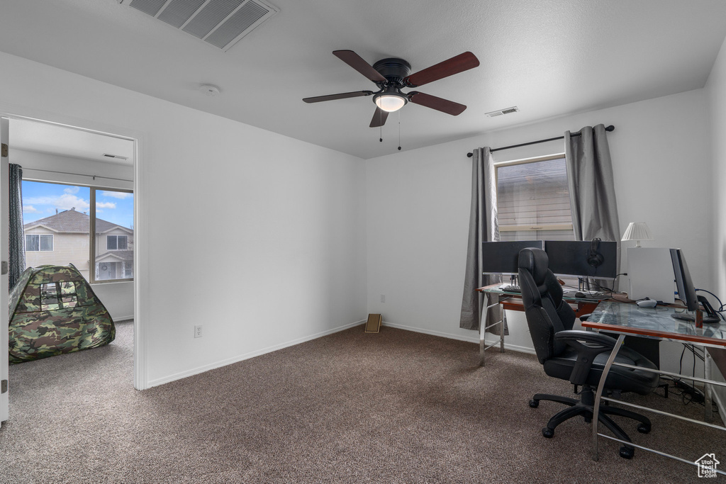Office area featuring ceiling fan and dark carpet