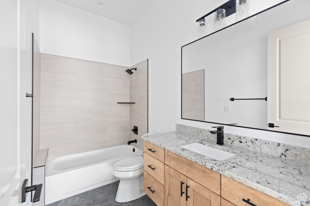 Full bathroom featuring vanity, tile floors, toilet, and tiled shower / bath