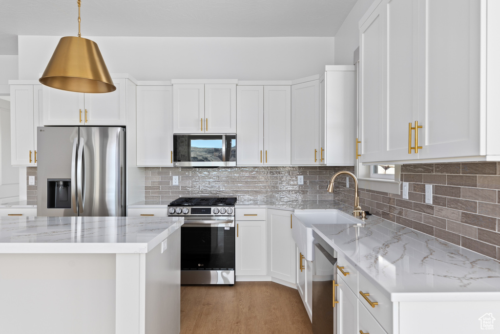 Kitchen featuring light hardwood / wood-style floors, backsplash, white cabinetry, and stainless steel appliances