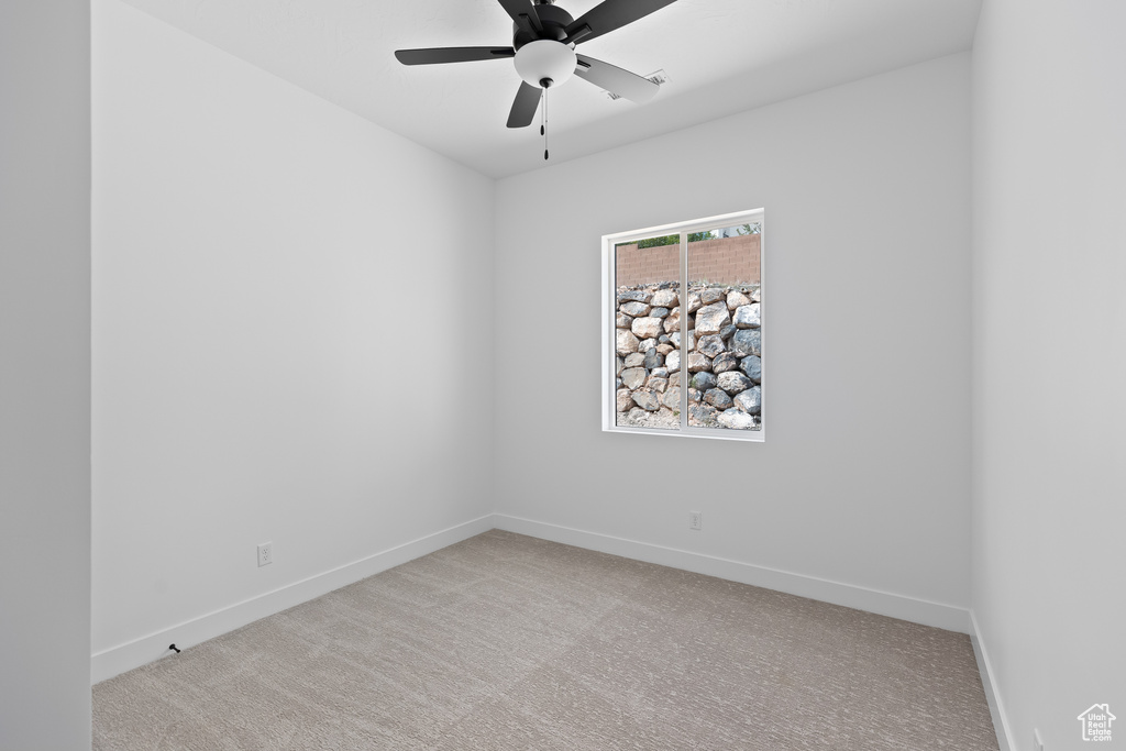 Empty room with light colored carpet and ceiling fan
