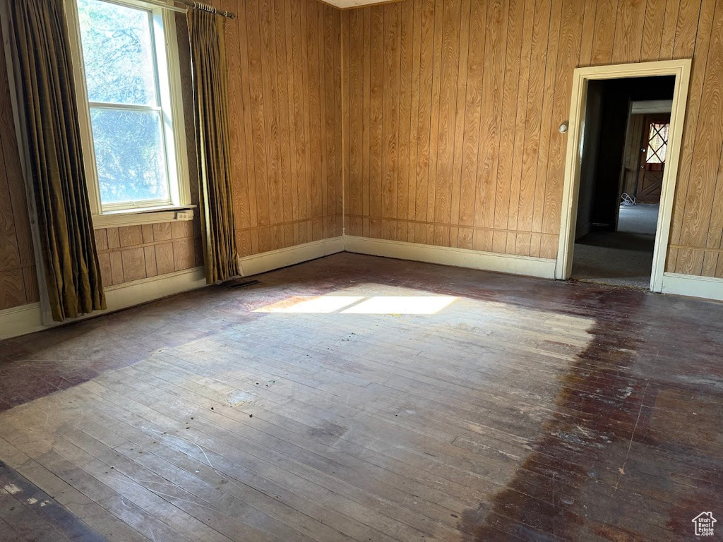 Empty room with wooden walls and hardwood / wood-style flooring