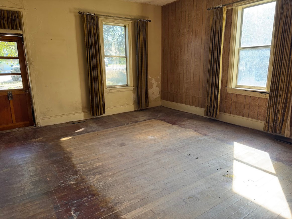 Empty room with wood walls and hardwood / wood-style flooring