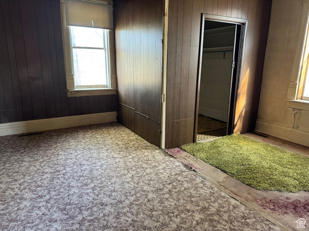 Unfurnished bedroom with wooden walls, a closet, and carpet